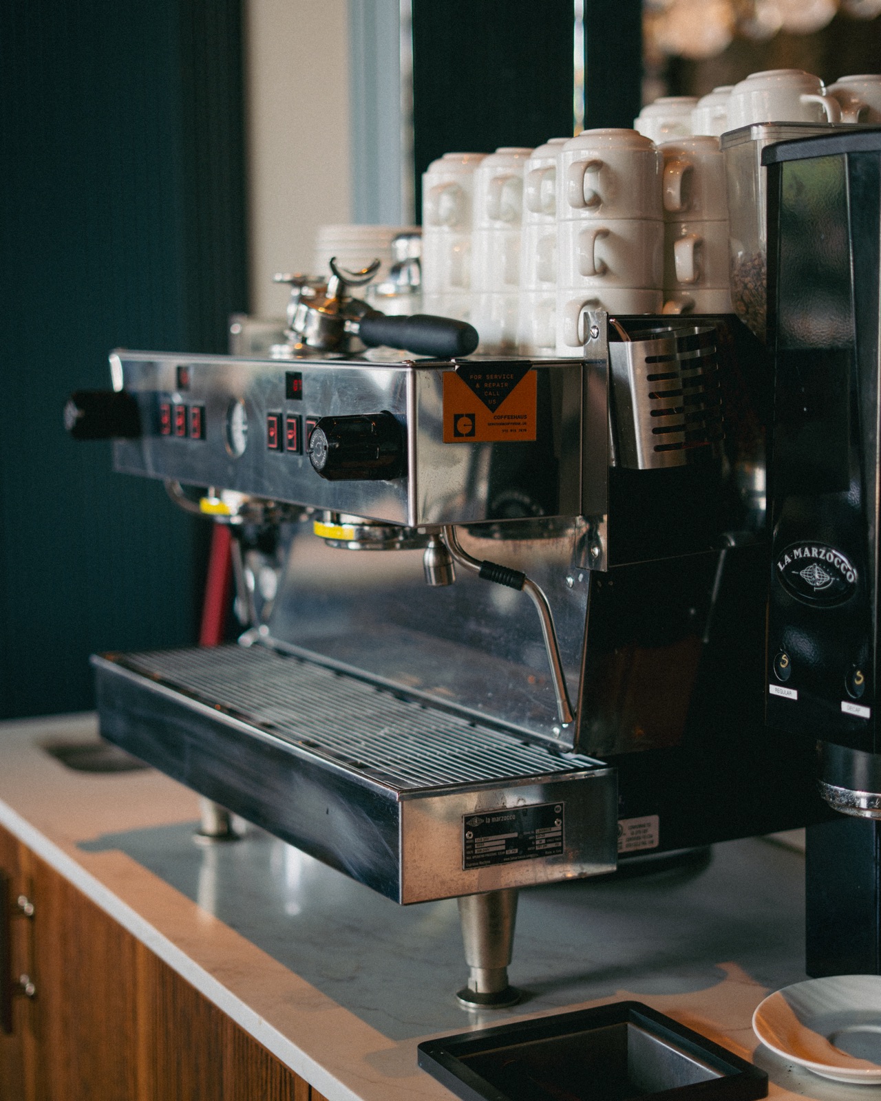 Godfrey Hotel's La Marzocco espresso machine with the Coffeehaus service and repair sticker on the front panel