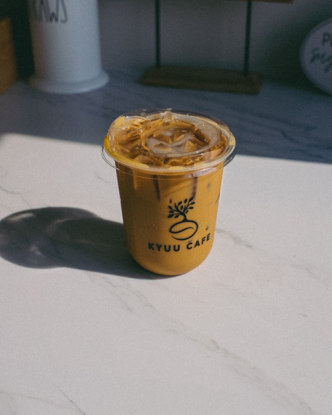Iced brown butter brown sugar latte in a Kyuu Cafe cup on marble